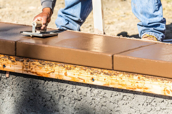 Строитель с помощью паха на мокрой цементной формовки справляется с новым бассейном