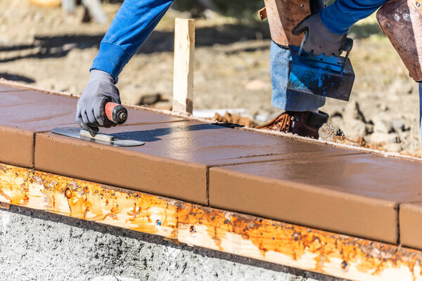 Строитель с помощью лопатки на мокрой цементной формовки справляется с новым бассейном