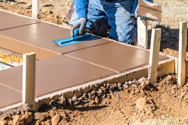Trabalhador da construção civil usando espátula em cimento molhado formando enfrentamento em torno de nova piscina — Fotografia de Stock