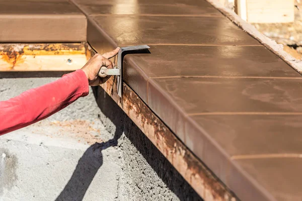 Trabajador de la construcción usando el borde del acero inoxidable en el cemento húmedo que forma el hacer frente alrededor de la piscina nueva —  Fotos de Stock