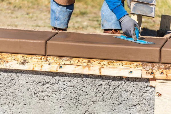 Travailleur de la construction utilisant la truelle sur ciment humide formant coping autour d'une nouvelle piscine — Photo