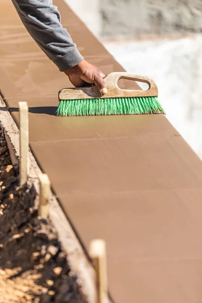 Trabajador de construcción usando cepillo en cemento húmedo formando hacer frente a la nueva piscina — Foto de Stock