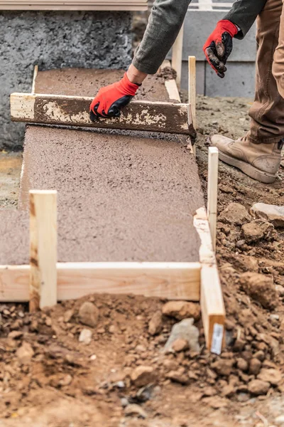 Trabajador de la construcción nivelación de cemento húmedo en el marco de madera —  Fotos de Stock