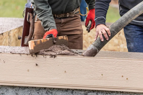 Byggnadsarbetare hälla och utjämning våt cement i trä inramning. — Stockfoto