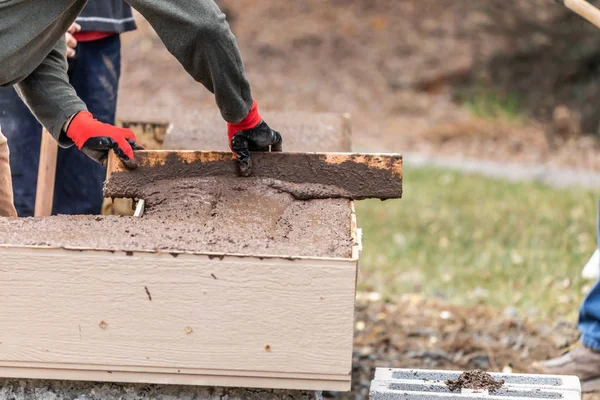 Строитель выравнивает мокрый цемент в деревянную раму — стоковое фото