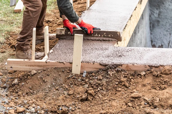 Bauarbeiter ebnet nassen Zement in Holzrahmen — Stockfoto