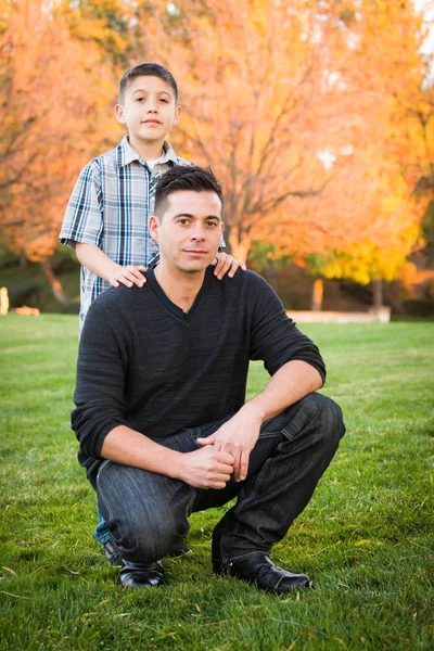 Pai e filho hispânicos retrato contra árvores coloridas queda — Fotografia de Stock