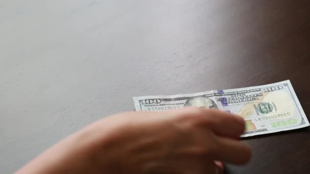 女人的手在桌上为男人数着一百美元的钞票 — 图库视频影像