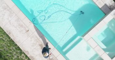 Overhead Aerial of Woman Vacuuming Swimming Pool