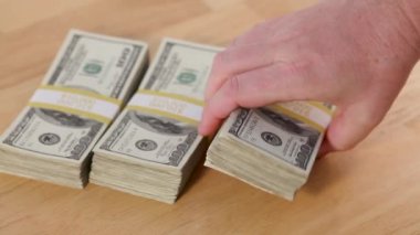 Adam 100 Dolarlık banknotları masaya yatırıp piramidin içine koyuyor.