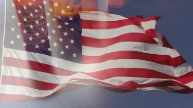 4k Slow Motion İlaç Şişeleri ve Hayalet Amerikan Bayrağı Dalgasıyla Düşen Haplar. İlaç şişesi etiketleri hayali isimler, adresler ve stok fotoğrafçılığı endüstrisi için özel olarak tasarlanmış bilgilerle tescilli değildir..