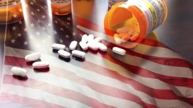 4k Slow Motion İlaç Şişeleri ve Hayalet Amerikan Bayrağı Dalgasıyla Düşen Haplar. İlaç şişesi etiketleri hayali isimler, adresler ve stok fotoğrafçılığı endüstrisi için özel olarak tasarlanmış bilgilerle tescilli değildir..
