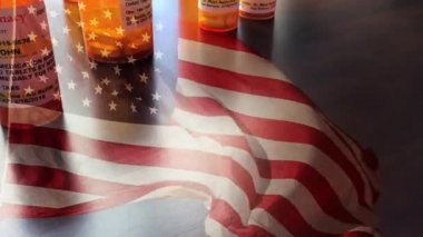 4k Slow Motion İlaç Şişeleri ve Hayalet Amerikan Bayrağı Dalgasıyla Düşen Haplar. İlaç şişesi etiketleri hayali isimler, adresler ve stok fotoğrafçılığı endüstrisi için özel olarak tasarlanmış bilgilerle tescilli değildir..