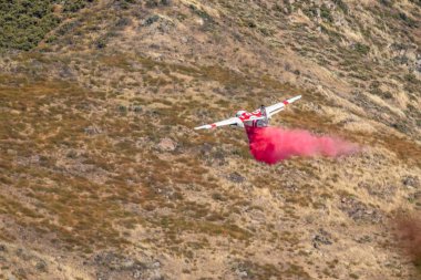 Winchester, CA USA - June 14, 2020: Cal Fire aircraft drops fire retardant on a dry hilltop wildfire near Winchester, California. clipart