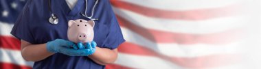 Doktor ya da Hemşire Eldiven Giyiyor Amerikan Bayrağı Üzerinde Domuz Kumbarası Tutuyor.