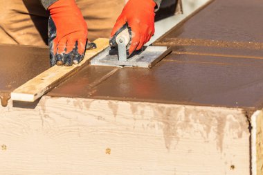 İnşaat işçisi ıslak çimentoya elle dokunarak yeni havuzun etrafını kontrol ediyor..