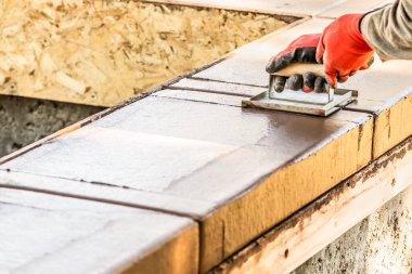 İnşaat işçisi ıslak çimentoya elle dokunarak yeni havuzun etrafını kontrol ediyor..