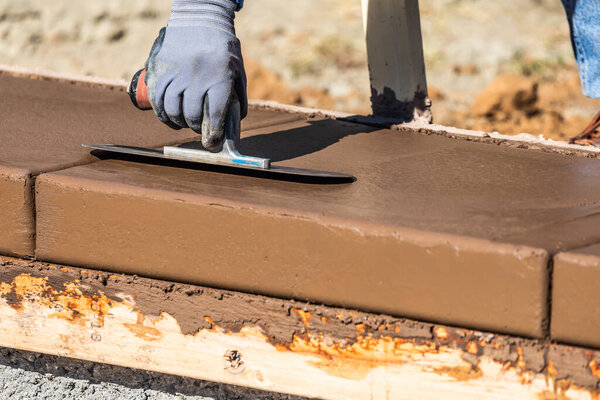 Строитель с помощью лопатки на мокрой цементной формовки справляется с новым бассейном.