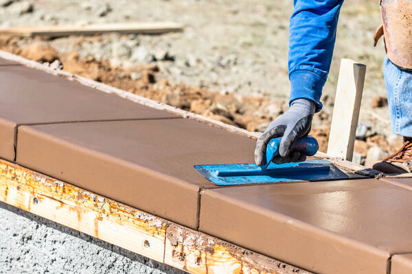 Строитель с помощью лопатки на мокрой цементной формовки справляется с новым бассейном.