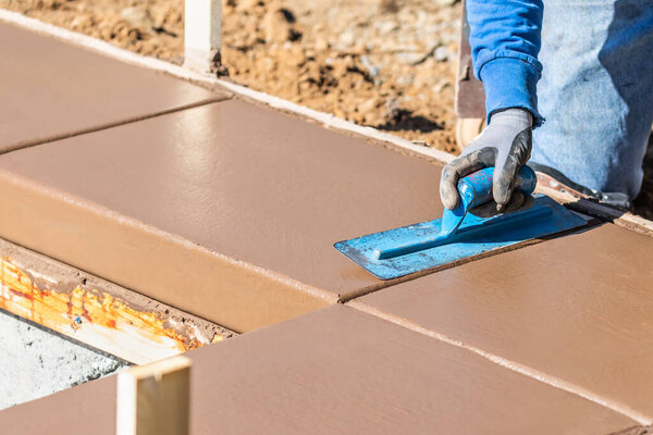 Строитель с помощью лопатки на мокрой цементной формовки справляется с новым бассейном.