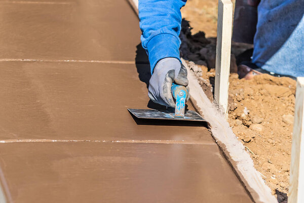 Строитель с помощью паха на мокрой цементной формовки справляется с новым бассейном.