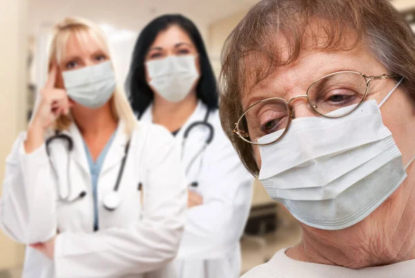 Senior Adult Female Κοιτάζοντας Κάτω Καθώς Γιατροί Στέκονται Πίσω Από — Φωτογραφία Αρχείου