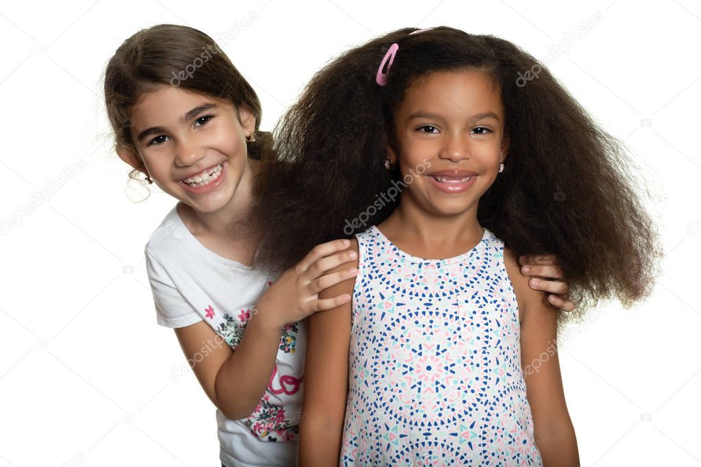 Cute hispanic and african-american small girls hugging with a smile - Isolated on white