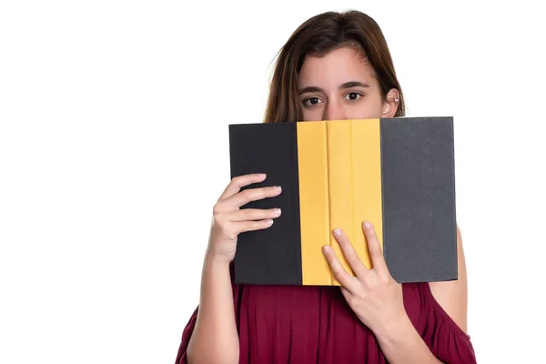 漂亮的少女把脸藏在一本书后面 在白色上被孤立 — 图库照片