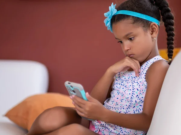 Pequeña chica afroamericana usando un teléfono móvil — Foto de Stock