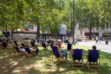 İnsanlar yazın keyfini çıkarıyor Londra 'nın merkezindeki Leicester Meydanı' nda.
