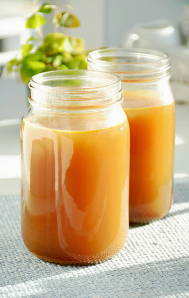 Home made bone and vegetable broth in glass jars  shot in natural light.  Healthy and nutritous.