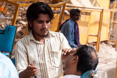 Adam dışarıda sakalını kesiyor.