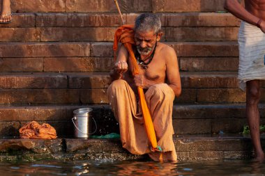 Ganj Nehri 'nin kutsal sularının yanında kendi yaptığı oltayla oturan yaşlı bir adam. Varanasi, Hindistan