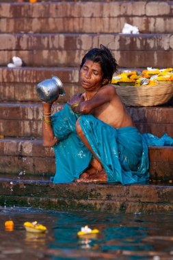 Mavi elbiseli bir kadın Ganj Nehri 'nin kutsal sularında gümüş bir kavanozda banyo yapıyor. Varanasi, Hindistan