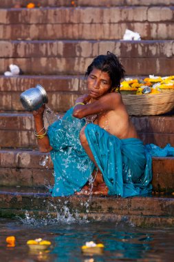 Mavi elbiseli bir kadın Ganj Nehri 'nin kutsal sularında gümüş bir kavanozda banyo yapıyor. Varanasi, Hindistan