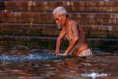 Ganj Nehri 'nin kutsal sularında yıkanan yaşlı bir adam. Varanasi, Hindistan