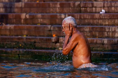 Ganj Nehri 'nin kutsal sularında yıkanan yaşlı bir adam. Varanasi, Hindistan