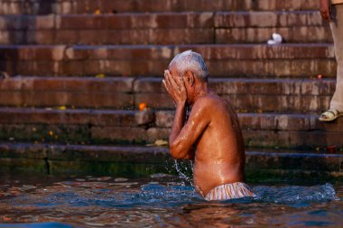 Ganj Nehri 'nin kutsal sularına gümüş kavanozdan su döken yaşlı adam. Varanasi, Hindistan