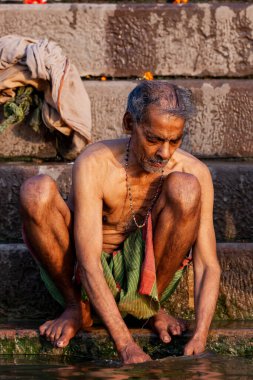 Ganj Nehri 'nin kıyısında oturan yaşlı adam. Varanasi, Hindistan