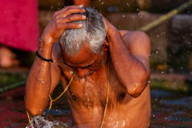 Ganj Nehri 'nin kutsal sularında yıkanan yaşlı bir adam. Varanasi, Hindistan