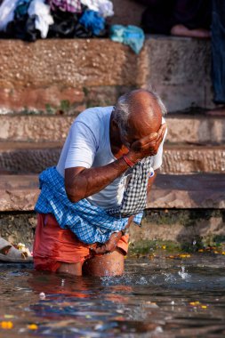 Yaşlı bir adam kendini yıkıyor ve Ganj Nehri 'nin kutsal sularını içiyor. Varanasi, Hindistan