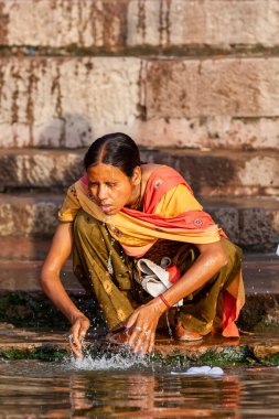 Renkli elbiseli bir kadın Ganj Nehri 'nin suyuyla yüzünü yıkıyor. Varanasi, Hindistan 