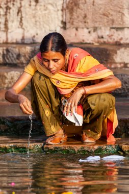 Renkli elbiseli bir kadın Ganj Nehri 'nin suyuyla yüzünü yıkıyor. Varanasi, Hindistan 