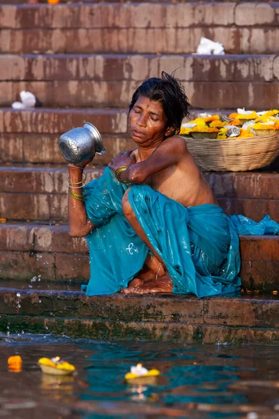 ガンジス川の聖水で銀の瓶から身を入浴青い服の女性 インドのバラナシ — ストック写真