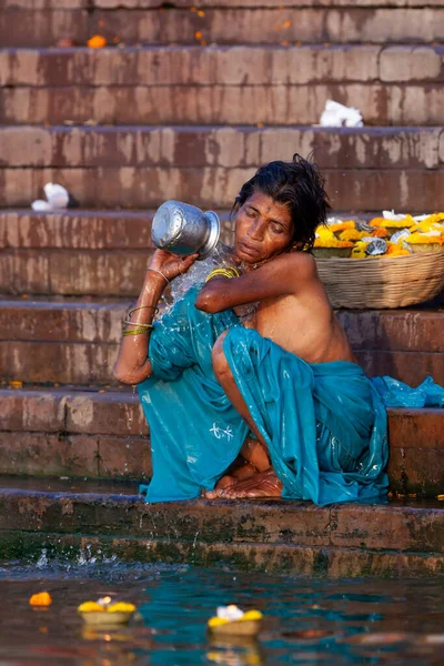 ガンジス川の聖水で銀の瓶から身を入浴青い服の女性 インドのバラナシ — ストック写真