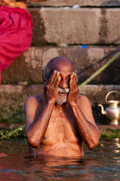 Ganj Nehri 'nin kutsal sularına gümüş kavanozdan su döken yaşlı adam. Varanasi, Hindistan