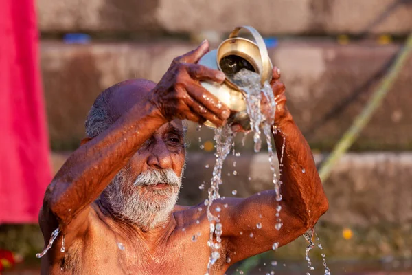 ガンジス川の聖水に銀瓶から水を注ぐ老人 インドのバラナシ — ストック写真