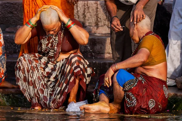 男性は女性の頭を剃り ガンジス川の神聖な水の横に座っている インドのバラナシ — ストック写真