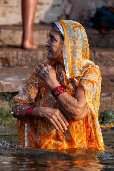 インド バラナシのガンジス川の聖水に立つ黄色いサリーの老婦人 — ストック写真