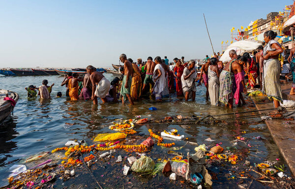 Индия, Варанаси - 23 апреля 2011 года: Неизвестные принимают ритуальные ванны в реке Ганга. Святая ритуальная баня проводится каждый день